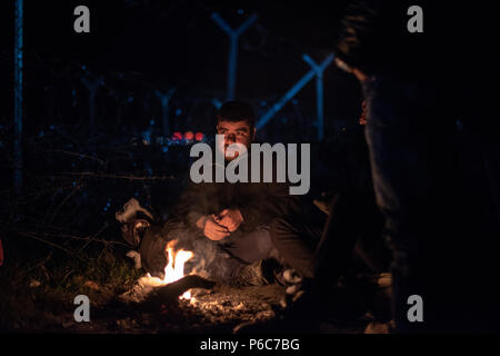 Flüchtling versuchen sich durch ein Feuer in der Nacht zu warm am provisorischen Flüchtlingslager der Greek-Macedonian Grenze in der Nähe des griechischen Dorf Idome Stockfoto