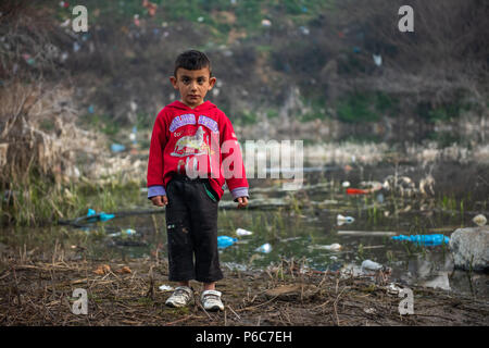 Flüchtlingskind spielen um einen kleinen stagnierenden Teich an der provisorischen Lager der Greek-Macedonian Grenze in der Nähe des griechischen Dorf Idomeni. Stockfoto