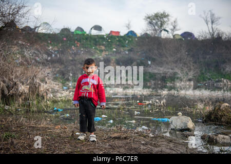 Flüchtlingskind spielen um einen kleinen stagnierenden Teich an der provisorischen Lager der Greek-Macedonian Grenze in der Nähe des griechischen Dorf Idomeni. Stockfoto