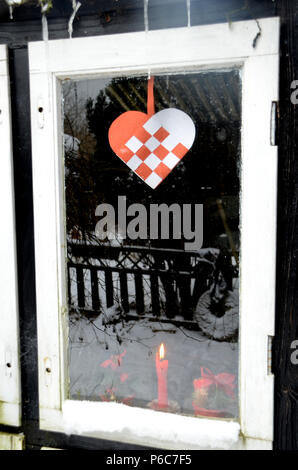 Fenster mit Weihnachtsschmuck widerspiegelt einen verschneiten Garten Landschaft. Stockfoto
