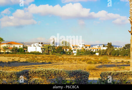 Landschaft der Stadt Paphos mit Häuser, Bäume und Berge im Hintergrund gegen den blauen Himmel, Zypern. Fotos warmen Farben der untergehenden Sonne Stockfoto