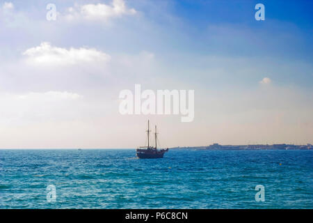 Dunkle Silhouette des Schiffes im Meer bei Sonnenuntergang, weißen Licht der untergehenden Sonne auf dem Wasser. Sail yacht Silhouette bei Sonnenuntergang in der Entfernung. Meer in Abend Stockfoto