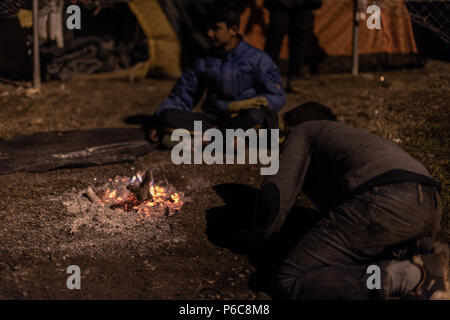 Flüchtling versuchen sich durch ein Feuer in der Nacht zu warm am provisorischen Flüchtlingslager der Greek-Macedonian Grenze in der Nähe des griechischen Dorf Idome Stockfoto