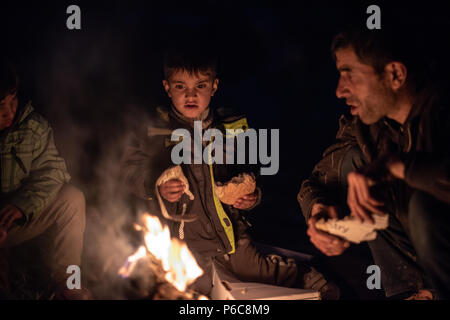 Flüchtling versuchen sich durch ein Feuer in der Nacht zu warm am provisorischen Flüchtlingslager der Greek-Macedonian Grenze in der Nähe des griechischen Dorf Idome Stockfoto