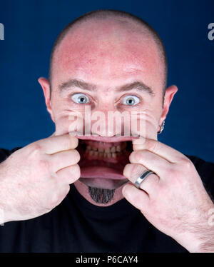 Mann seinen Mund stretching ein lustiges Gesicht machen, Studio shot Stockfoto