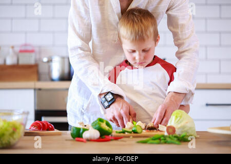 Bild des Menschen und sein Sohn die Zubereitung von Speisen am Tisch mit Gemüse Stockfoto