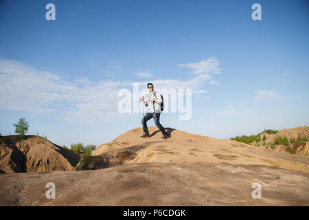 Bild aus der Ferne von touristischen Mann mit Stöcken auf dem Hügel Stockfoto