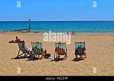 "Oh, wir wollen neben der Küste sein!" Und die Menschen entspannen und genießen den Sommer Sonne am Sandstrand zwischen Boscombe und Bournemouth Stockfoto