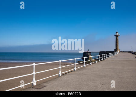 Whitby pier, weißen Geländer führt zu einem alten Stein Leuchtturm Stockfoto