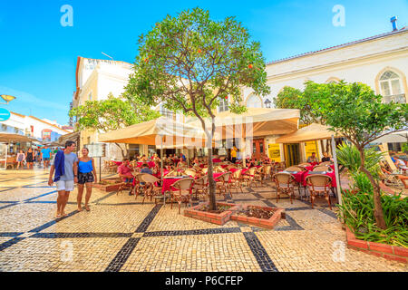 Lagos, Portugal - 19 August 2017: Typisch portugiesische gepflasterte Fußgängerzone. Restaurants und Geschäfte in der Altstadt von Lagos, einer historischen Badeort an der Algarve Küste. Sommer Saison. Urbane Stadtbild. Stockfoto