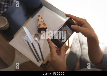 Schwangere Frau unter Foto von Gebäck mit Handy Stockfoto