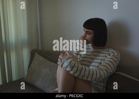 Besorgt Frau sitzt auf einem Sofa im Wohnzimmer. Stockfoto