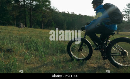 Fat bike auch fatbike oder Fat Tire Bike im Sommer Reiten im Wald. Der Kerl fährt Fahrrad zwischen Bäumen und Stümpfe. Er überwindet einige obstac Stockfoto