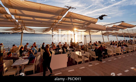 Insel Ibiza, Spanien - 1. Mai 2018: Menschenmassen, den Sonnenuntergang von der Terrasse am Meer von Savannah Café Treffen, an der Westküste von Ibiza. Diese Stockfoto