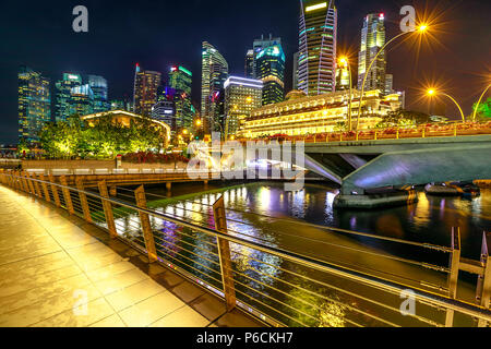 Singapore Downtown Skyline mit Wolkenkratzern des Geschäftsviertels von der Fußgängerbrücke in der Marina Bay Promenade. Singapur mit die Lichter der Nacht reflektiert in der Bucht. Stockfoto