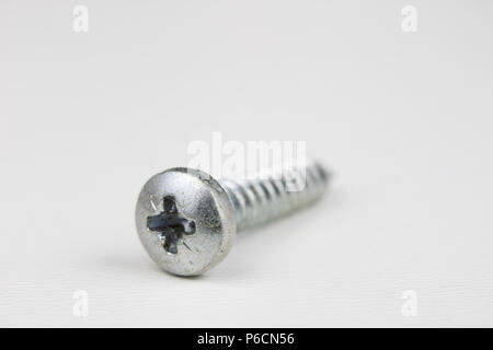 Schraubenkopf auf einem weißen Tisch. Zubehör für Schraubverbindungen. Hellen Hintergrund. Stockfoto