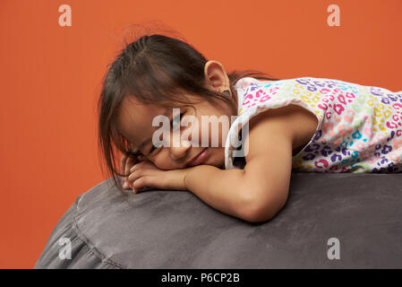 Portrait von traurigen asiatischen Mädchen auf orange Farbe Hintergrund isoliert Stockfoto