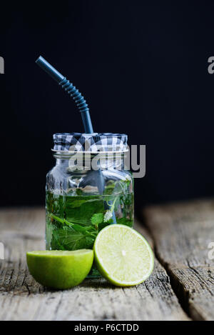 Zitrusfrüchte und Kräutern infundiert Sassi Wasser für Detox oder Diäten in Glasflaschen auf Holzbrett, dunklen Hintergrund. Stockfoto