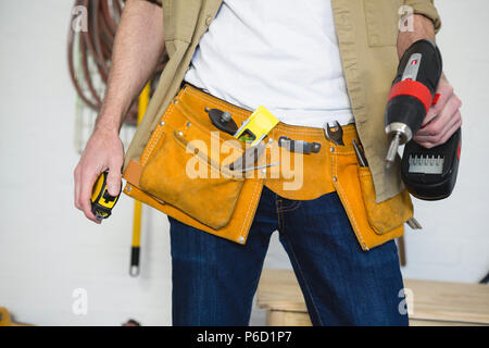 Männliche Tischler mit Werkzeug Gürtel in Werkstatt Stockfoto