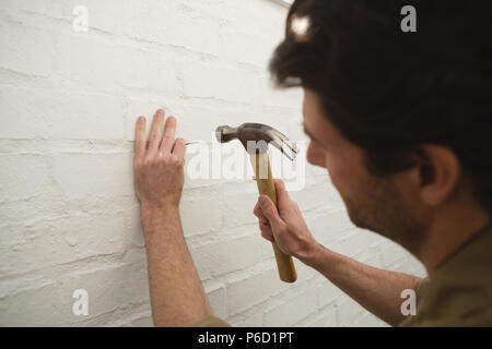 Männliche Tischler hämmern Nagel an der Wand Stockfoto