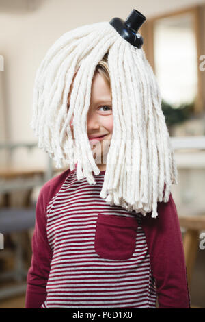 Happy Boy mit Mop auf dem Kopf in der Küche Stockfoto
