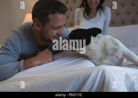 Paar spielen mit ihren Hund im Schlafzimmer Stockfoto