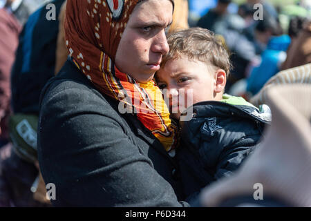 Ein flüchtling Mutter hält Ihr Kind, während sie wartet, in der Nähe der Grenze Tor der Grenze am provisorischen Flüchtlingslager der Greek-Macedonian borde zu überqueren Stockfoto