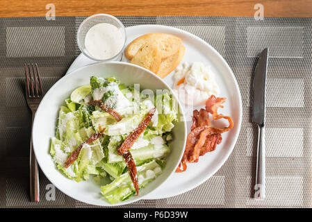 Caesar Salat mit knusprigem Speck und Eier pochieren serviert. Stockfoto