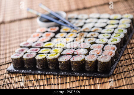 Sammlung von Sushi Maki auf Schiefer mit Sojasauce und Stäbchen. Stockfoto