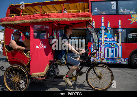 Trishaw erhält Touristen auf bakground der Sightseeing Bus in der Nähe des Kreml in Kazan Stadt, der Republik Tatarstan, Russland Stockfoto