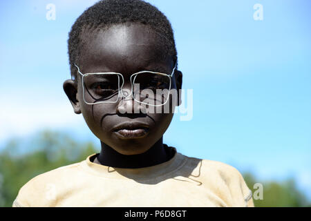 UGANDA, Karamoja, Kaabong, Dorf Lochom, Karamojong Stamm, Junge mit Kabel Spezifikationen/Junge mit Drahtbrille Stockfoto