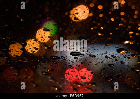 Bunte bokeh erschossen. Verkehr und Autos Nacht Stadt Fahrscheinwerfer und Regen fällt durch das Glas. Zusammenfassung Hintergrund Stockfoto