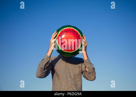 Ein Mann hält eine Wassermelone Ballon über sein Gesicht, Sommerzeit Konzept Stockfoto