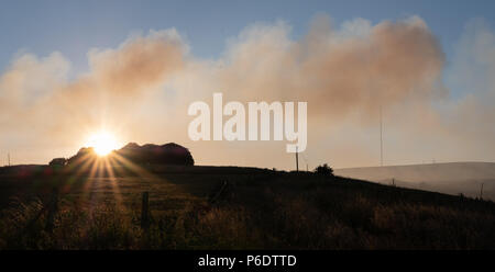 West Pennine Moors, UK, 29. Juni 2018. Die Abendsonne scheint durch den Rauch von den Bränden auf die West Pennine Moors im Winter Hill. Winter Hill TV-Mast kann durch den Rauch aus dem nahe gelegenen Brände gesehen werden. Stockfoto