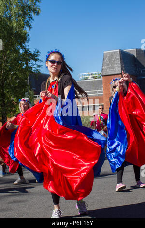 Tänzerin beim Betrachten der Kamera in Preston, Lancashire. Wetter in Großbritannien. 30/06/2018. Entertainer beim Lancashire Science Festival. Anna Debbage führt die Preston Samba Dancers an der University of Central Lancashire an, um einen traditionellen Sundance zur Musik der Worldwise Samba Drummers aufzuführen. Die Tanztruppe begrüßte die Besucher mit roten und blauen Spielmustern, die vom afro-brasilianischen Karneval und der Candomble-Musik inspiriert wurden. Quelle:MediaWorldImagesAlamyLiveNews. Stockfoto