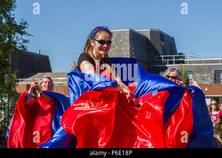 Tänzer, der die Kamera anschaut. Entertainer beim Lancashire Science Festival. Anna Debbage führt die Preston Samba Dancers an der University of Central Lancashire an, um einen traditionellen Sundance zur Musik der Worldwise Samba Drummers aufzuführen. Die Tanztruppe begrüßte die Besucher mit roten und blauen Spielmustern, die vom afro-brasilianischen Karneval und der Candomble-Musik inspiriert wurden. Preston, Lancashire. Juni 2018. Entertainer beim Lancashire Science Festival. Stockfoto