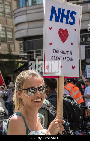 London, Großbritannien. 30 Juni, 2018. Eine Frau lächelt in die Kamera mit ihrem Plakat hoch hielt. Mit dem NHS 70 Jahre alt in diesem Jahr Tausende marschierten durch die Innenstadt von London in einer nationalen Rallye Support für die Dienstleistung zu zeigen und mehr Geld von der Regierung zu fordern. David Rowe/Alamy leben Nachrichten Stockfoto