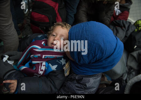 Mutter halten sie ihren Sohn in der Nähe des Gate, wie sie warten die Greece-Macedonia Grenze am provisorischen Flüchtlingslager in der Nähe der griechischen Dorf Idomen zu überqueren Stockfoto