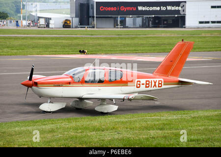 Socata TB 9 festen Kotflügel Flugzeug mit der Registrierung G-BIXB in Cardiff Wales Flughafen geparkt. Das Gebäude des Terminals wird im Hintergrund Stockfoto