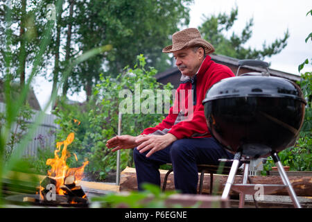 Grill Zeit. Europäischen Mann in hat Warten auf Gegrilltes. Stockfoto