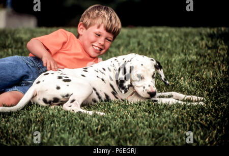 Happy Knabe spielt auf Gras mit seinem Dalmatiner Welpe HERR © Myrleen Pearson. Ferguson Cate Stockfoto