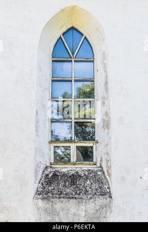 Mittelalterliche Kirche Fenster mit blauem Himmel und einem Baum spiegeln sich darin. Stockfoto