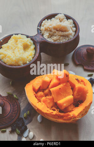 Vegetarische Weizen Porridge mit großen, hellen orange Stücke saftig gebratener Kürbis in einen Tontopf im rustikalen Stil. Ökologische Lebensmittel Stockfoto