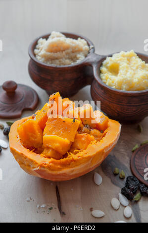 Vegetarische Weizen Porridge mit großen, hellen orange Stücke saftig gebratener Kürbis in einen Tontopf im rustikalen Stil. Ökologische Lebensmittel Stockfoto