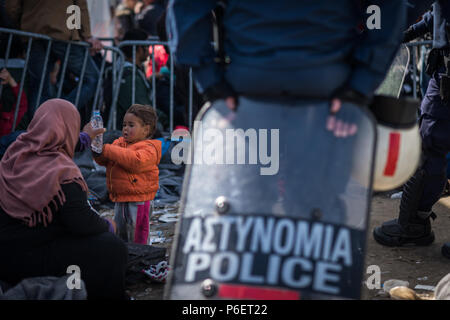 Mutter gibt ihr Kind Wasser aus einer Flasche zu trinken, in der Nähe des Gate, wie sie warten die Greece-Macedonia Grenze in den provisorischen Flüchtlingslagern zu überqueren, Ca Stockfoto