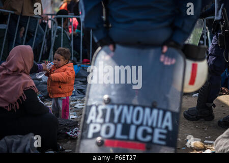 Mutter gibt ihr Kind Wasser aus einer Flasche zu trinken, in der Nähe des Gate, wie sie warten die Greece-Macedonia Grenze in den provisorischen Flüchtlingslagern zu überqueren, Ca Stockfoto