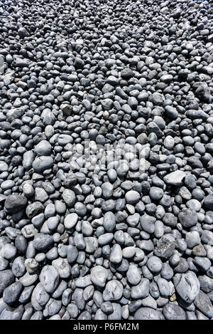 Runde dunkel gefärbte Felsen auf einer felsigen Küste Strand in Oregon. Stockfoto