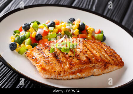 Gegrilltes Steak Lachs mit Paprika, Mais, Blaubeere und Zwiebel Salat closeup auf dem Teller auf dem Tisch. Horizontale Stockfoto