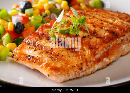 Gegrilltes Lachsfilet mit Salsa von Mais, Blaubeeren und Pfeffer Makro auf einem Teller. Horizontale Stockfoto