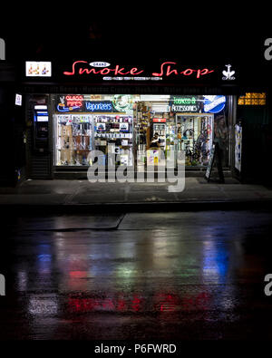 Juni 2, 2018 - New York, NY, USA - Rauch Shop Neonleuchten spiegeln sich in nassen Straßen von New York Stockfoto